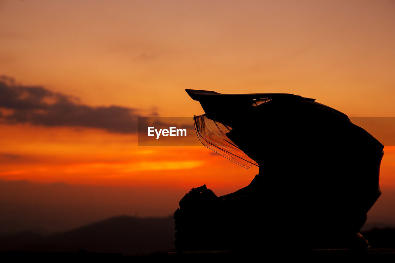 SILHOUETTE WOMAN SITTING AGAINST SKY DURING SUNSET