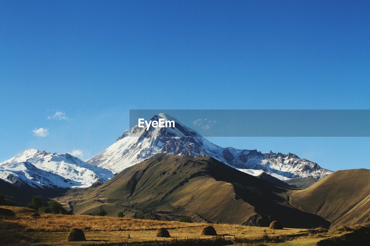 Scenic view of snowcapped mountain against blue sky