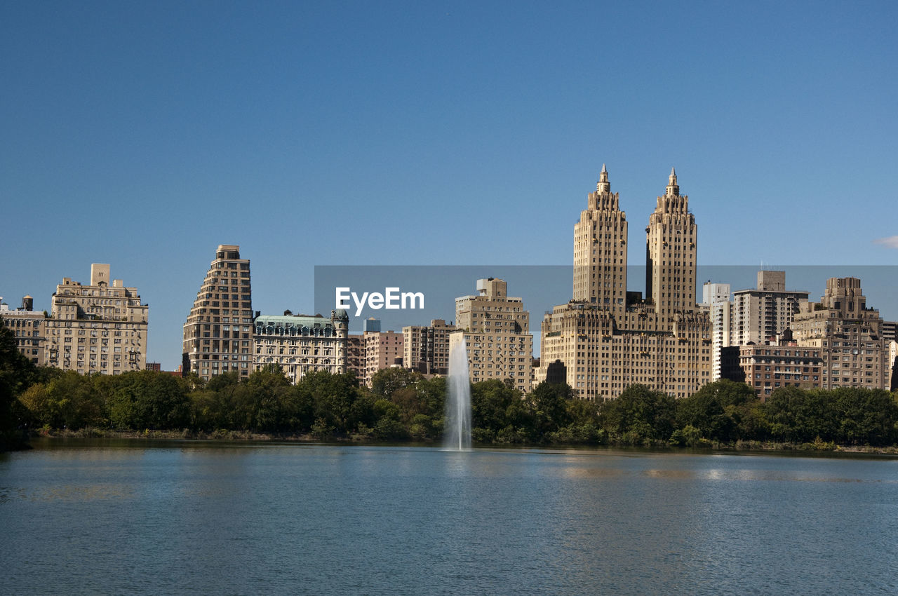 City at waterfront against clear sky