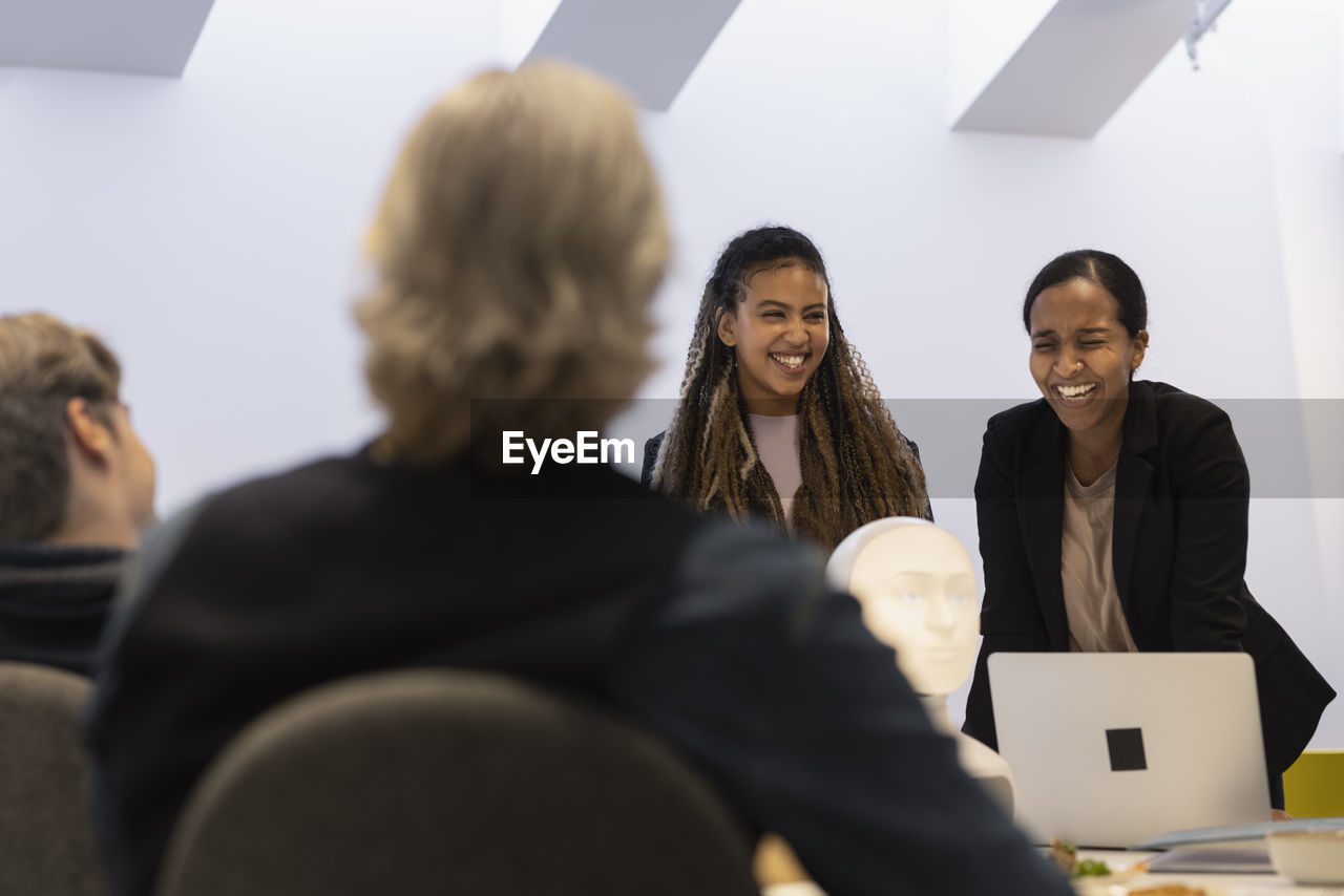 Business people discussing robot voice assistant during meeting