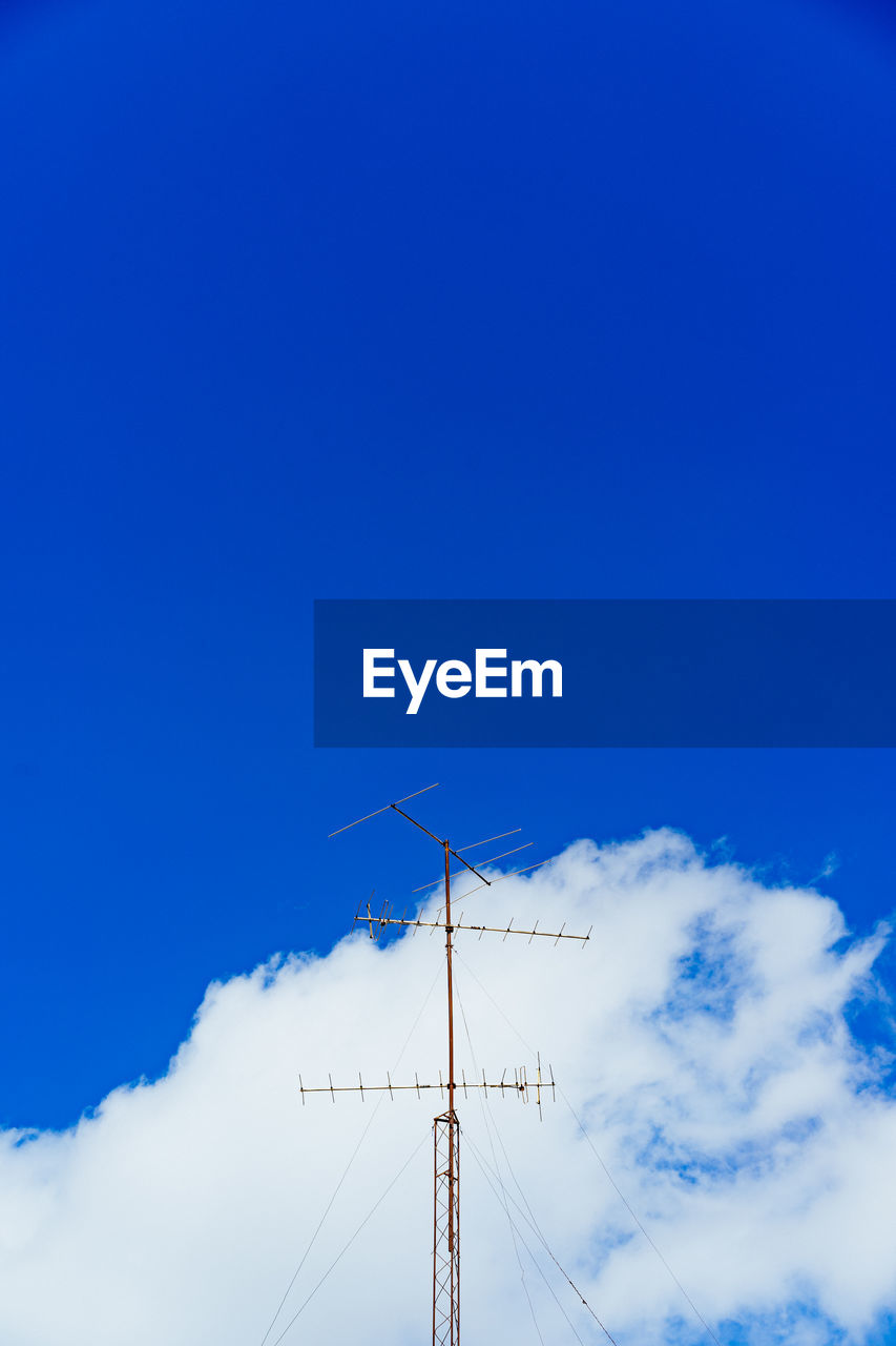 Low angle view of antennas against blue sky