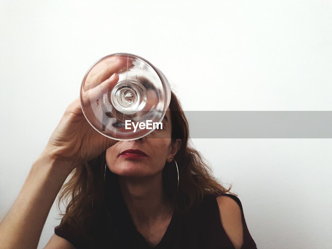 Portrait of woman holding drinking glass against white background