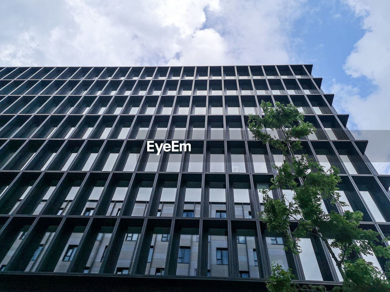 LOW ANGLE VIEW OF MODERN GLASS BUILDING AGAINST SKY