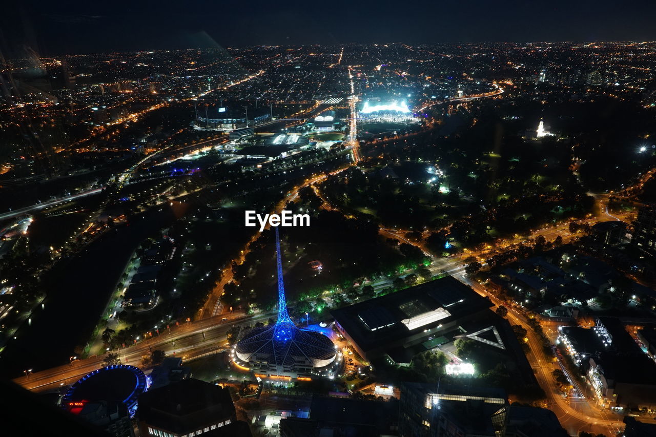 HIGH ANGLE VIEW OF ILLUMINATED CITY AGAINST SKY AT NIGHT