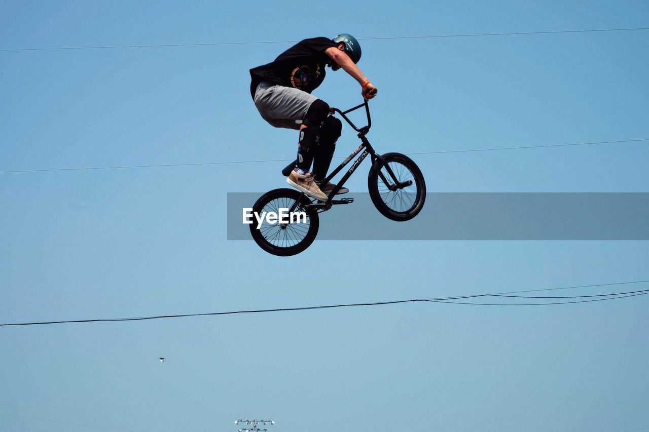 MAN RIDING BICYCLE AGAINST SKY