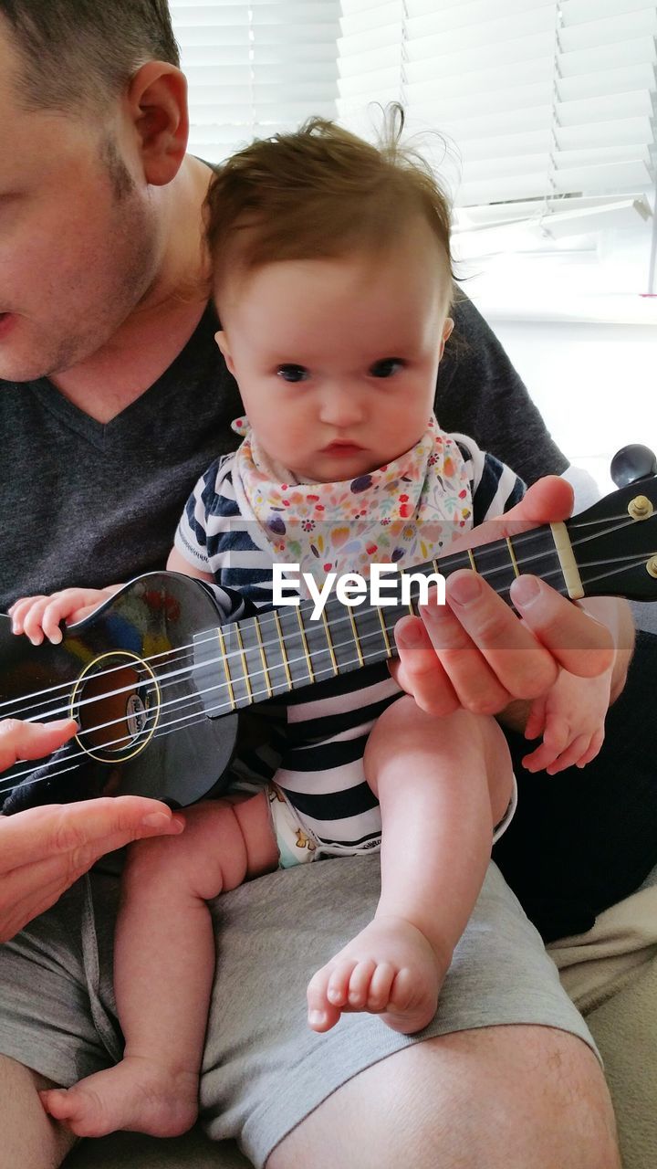 Father and daughter playing guitar at home