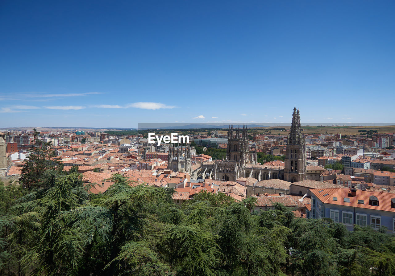 HIGH ANGLE VIEW OF BUILDINGS IN CITY AGAINST BLUE SKY