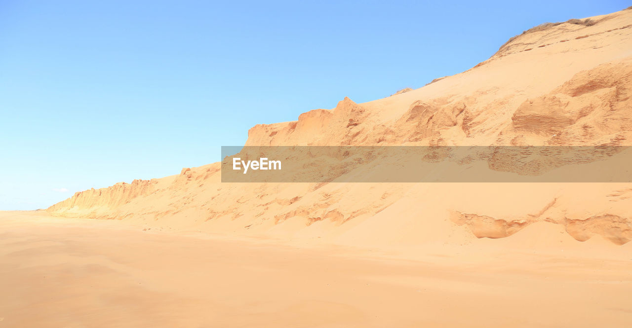 Sand dunes in desert against clear sky