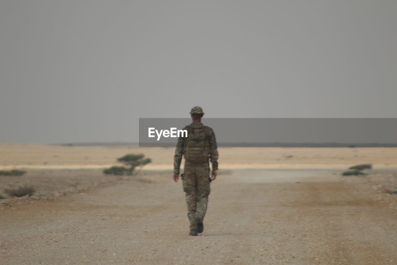 rear view of man standing on beach against clear sky