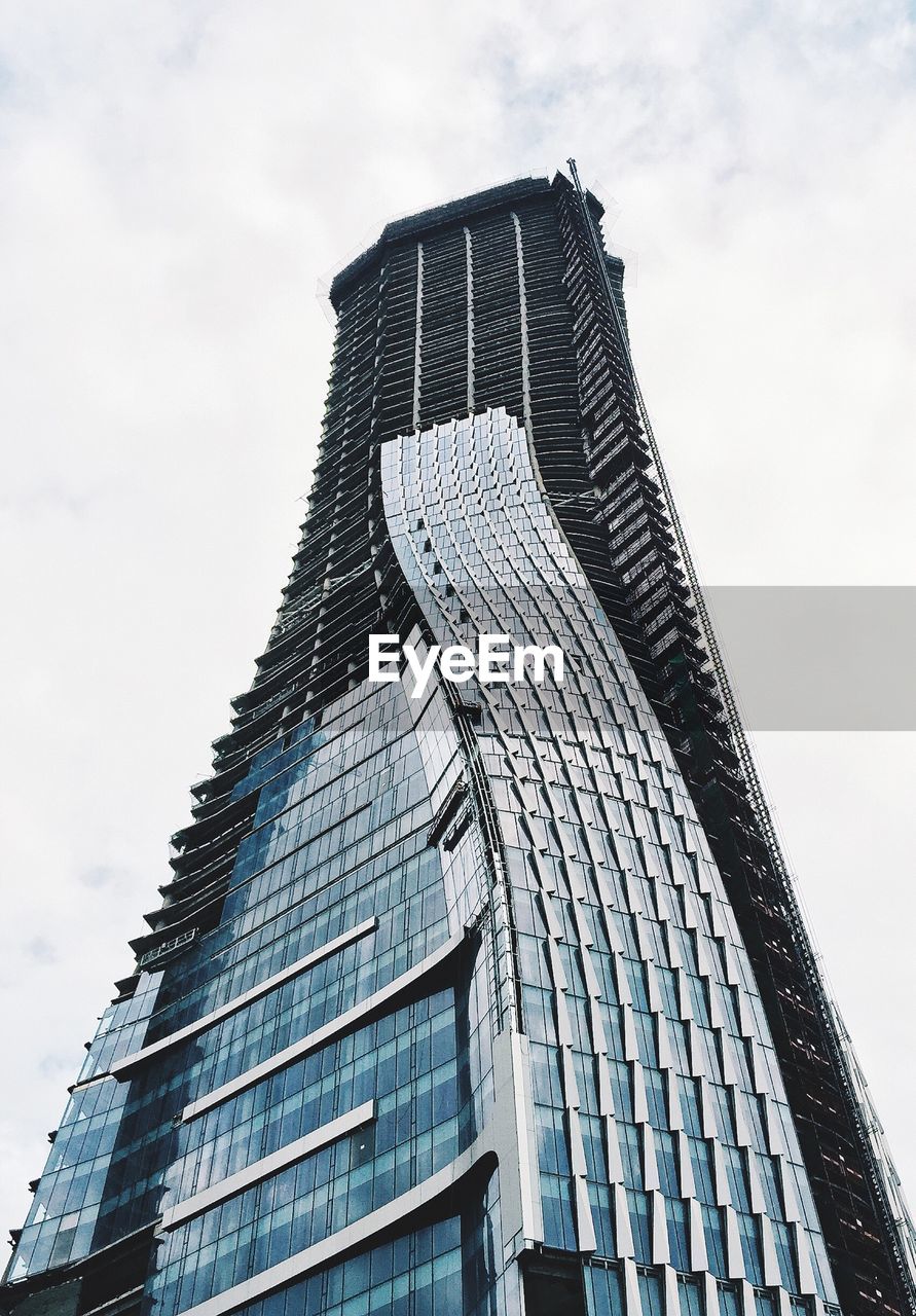 Low angle view of modern building against cloudy sky