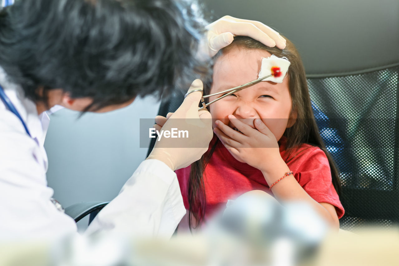 Doctor treating girl with wound at clinic