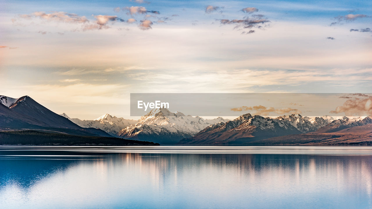 Scenic view of lake and snowcapped mountains against sky during sunset