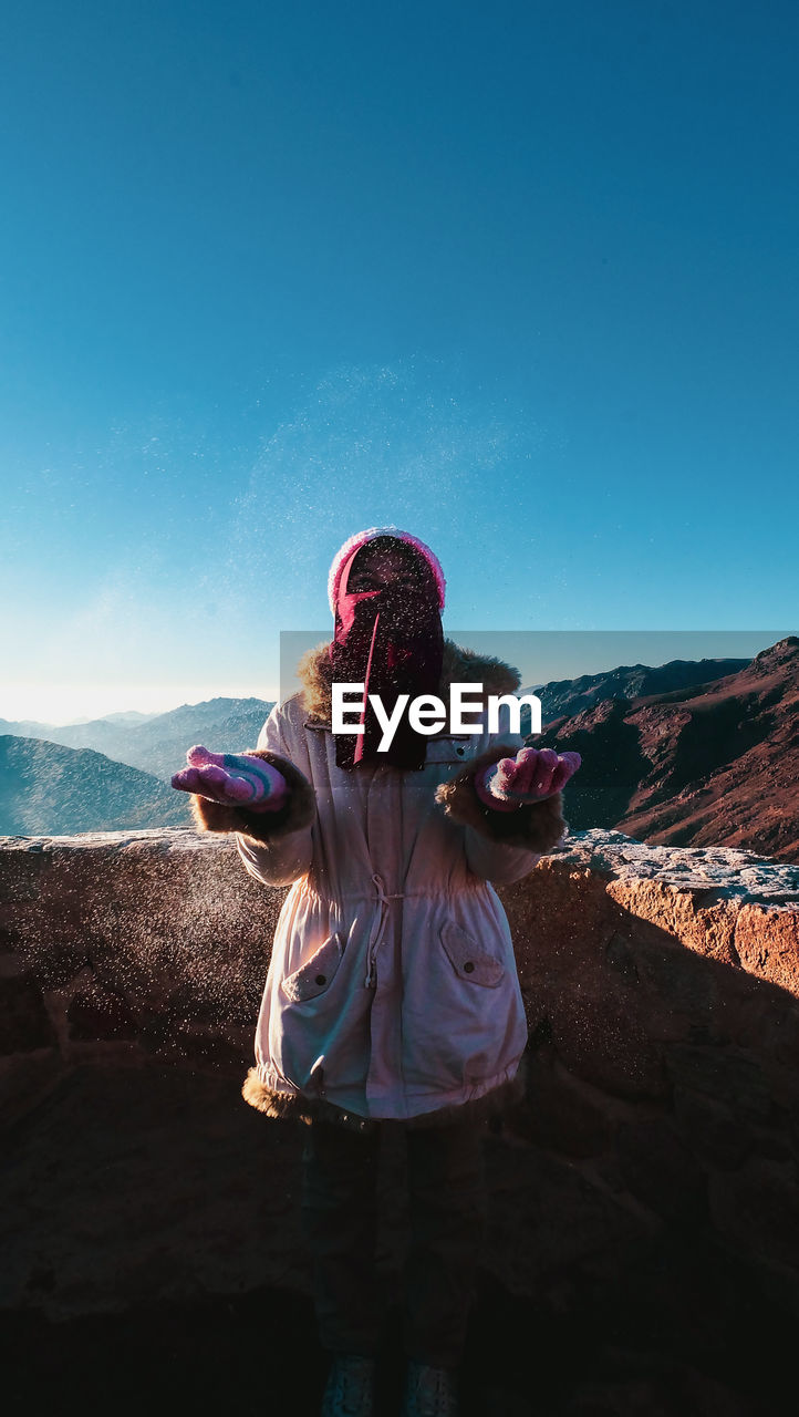 REAR VIEW OF WOMAN LOOKING AT MOUNTAIN AGAINST CLEAR SKY