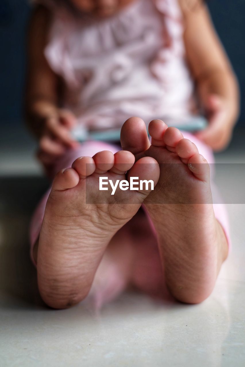 Low section of girl using digital tablet while sitting on floor