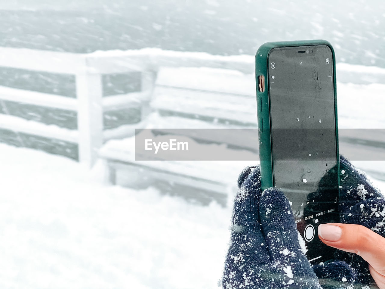 PERSON HOLDING SMART PHONE IN SNOW