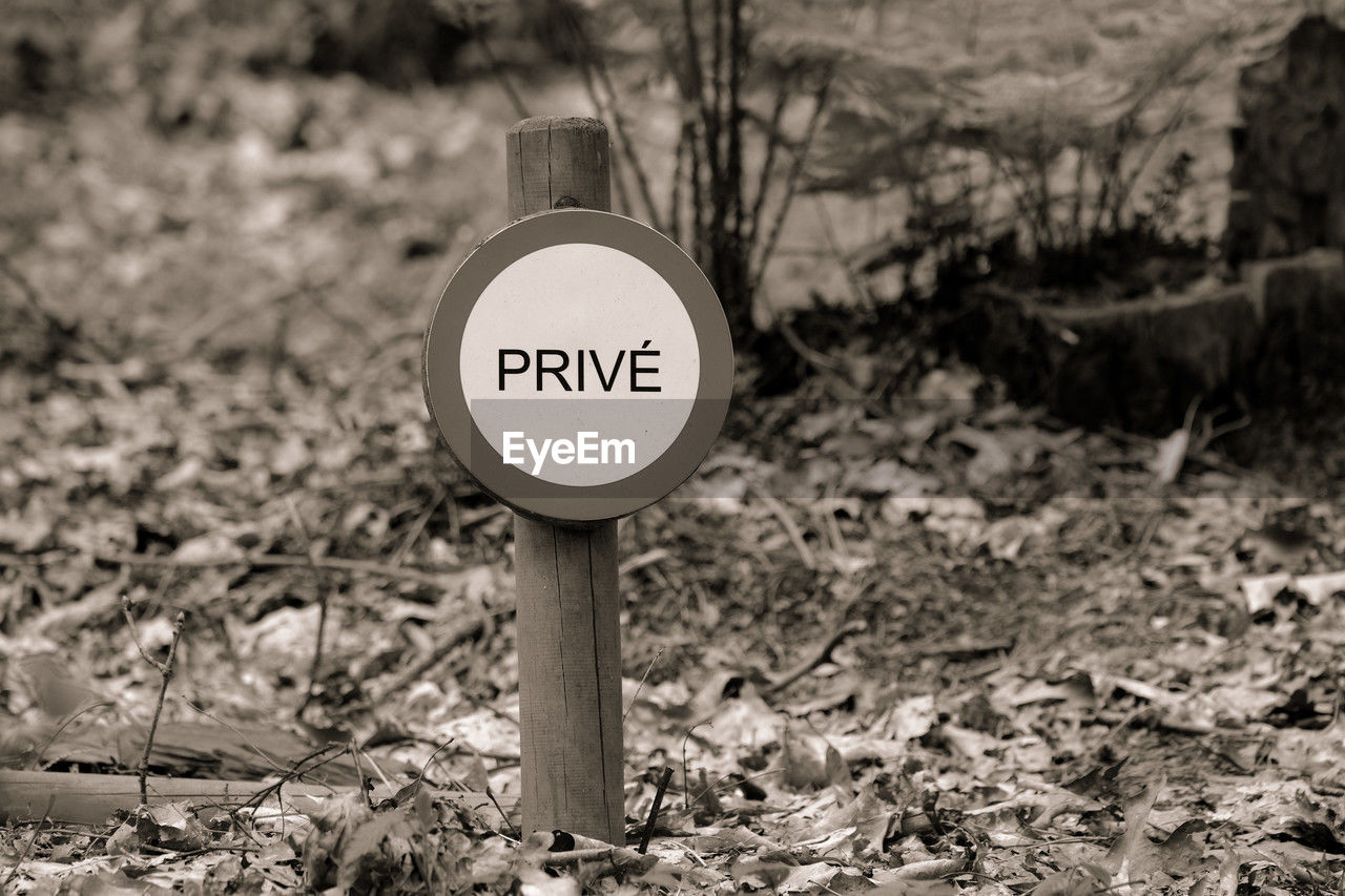 black and white, communication, sign, monochrome photography, monochrome, text, land, nature, no people, white, focus on foreground, day, western script, black, soil, guidance, warning sign, road sign, outdoors, information sign, field, tree, plant