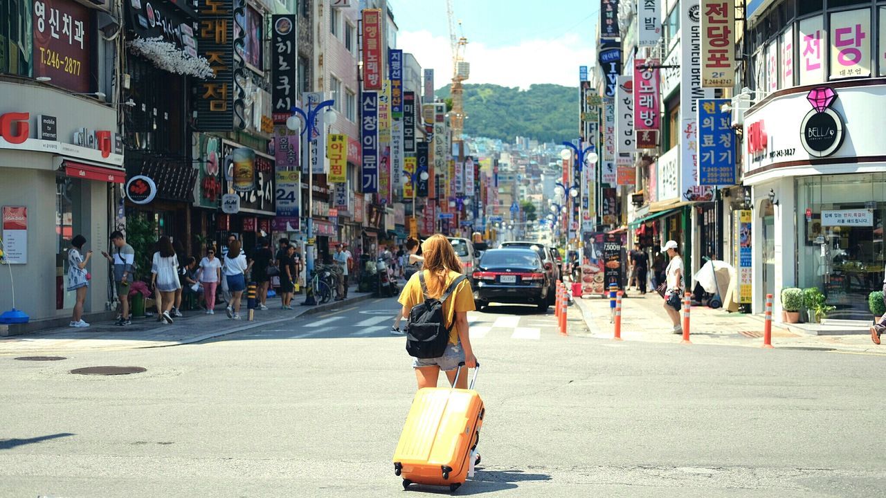 Woman with suitcase walking down south korean city street