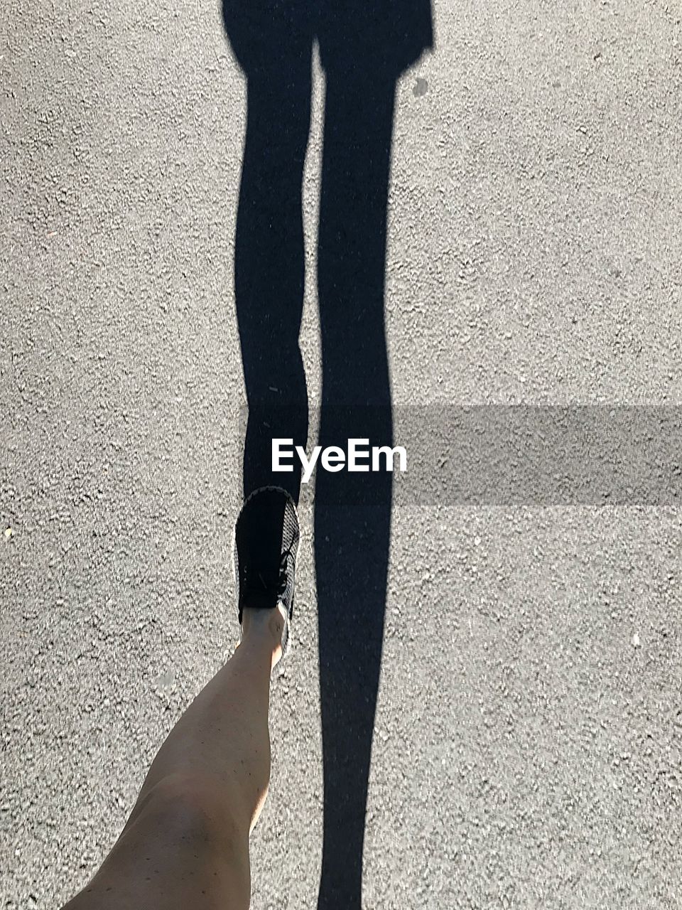 LOW SECTION OF PERSON STANDING ON SHADOW OF MAN
