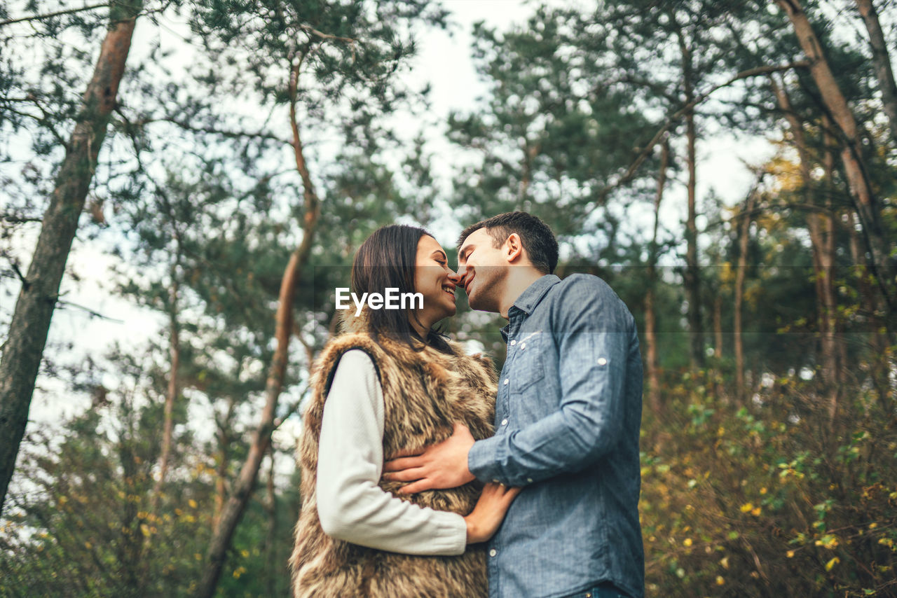Young couple kissing while standing in forest