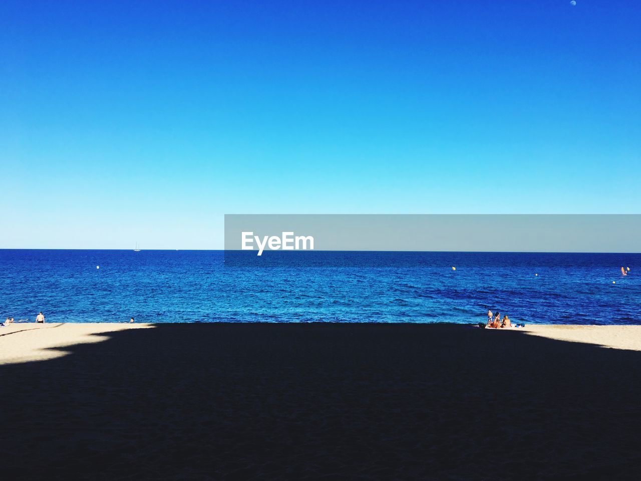 Scenic view of beach against clear blue sky