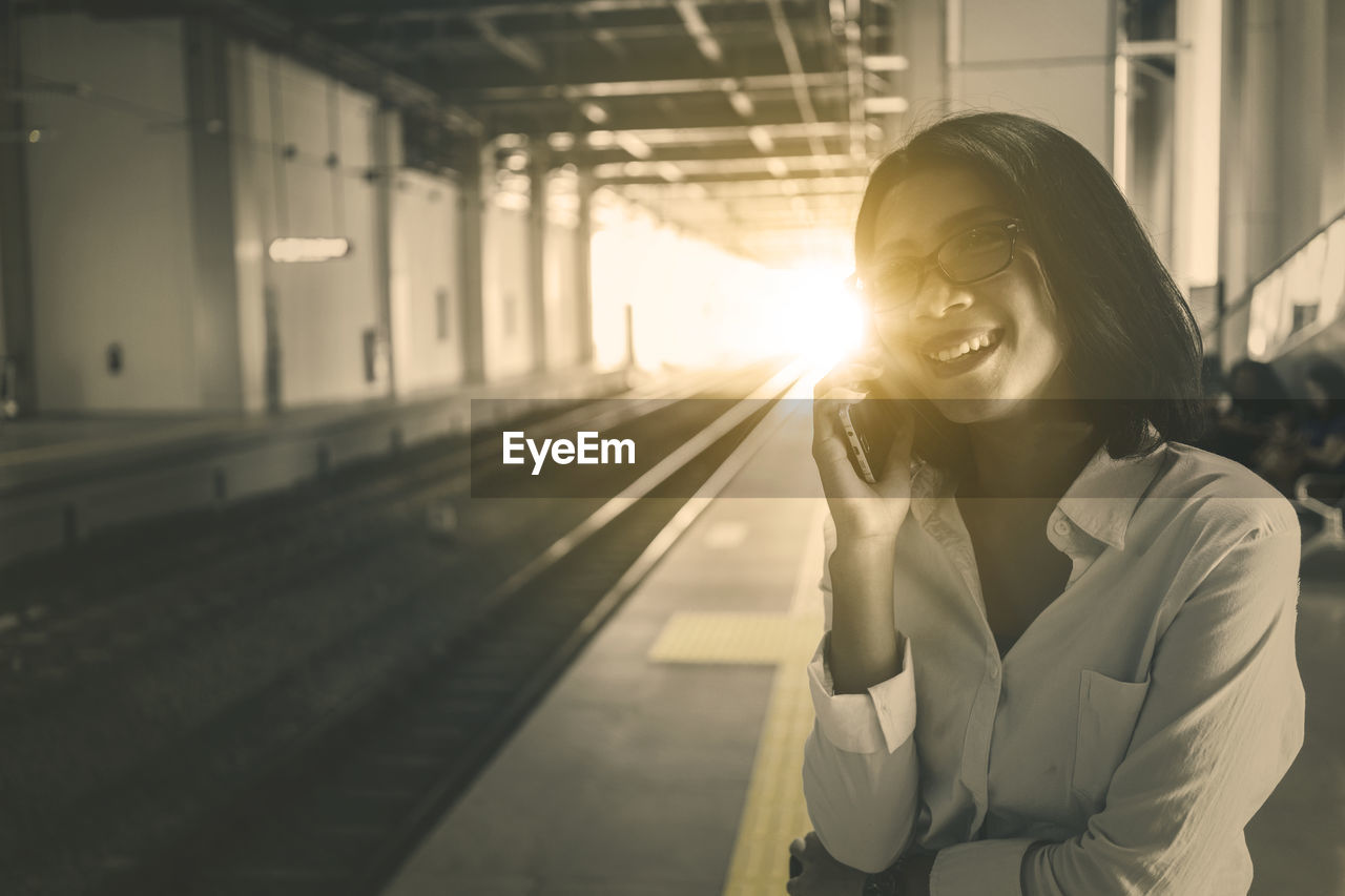 Young businesswoman walking on phone standing on railroad platform