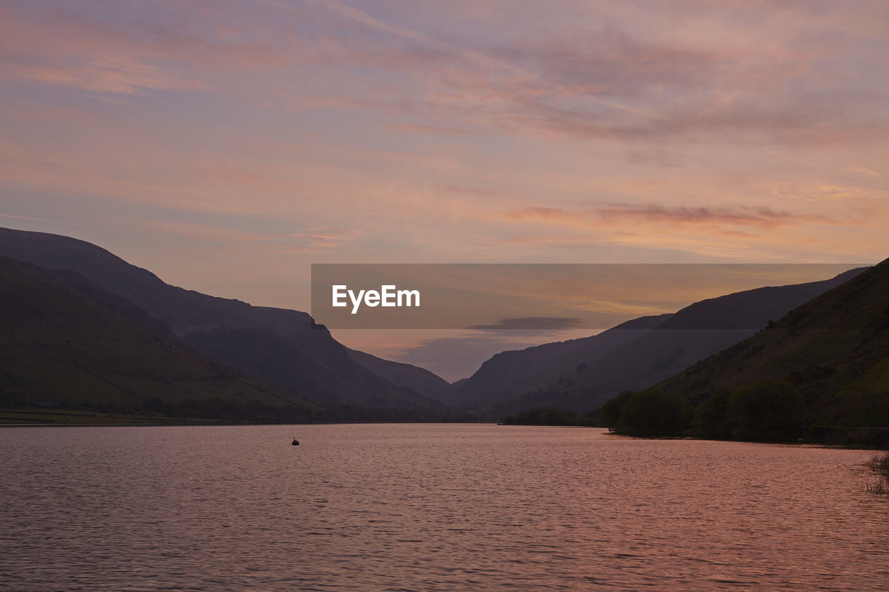 Scenic view of river through mountains against cloudy sky