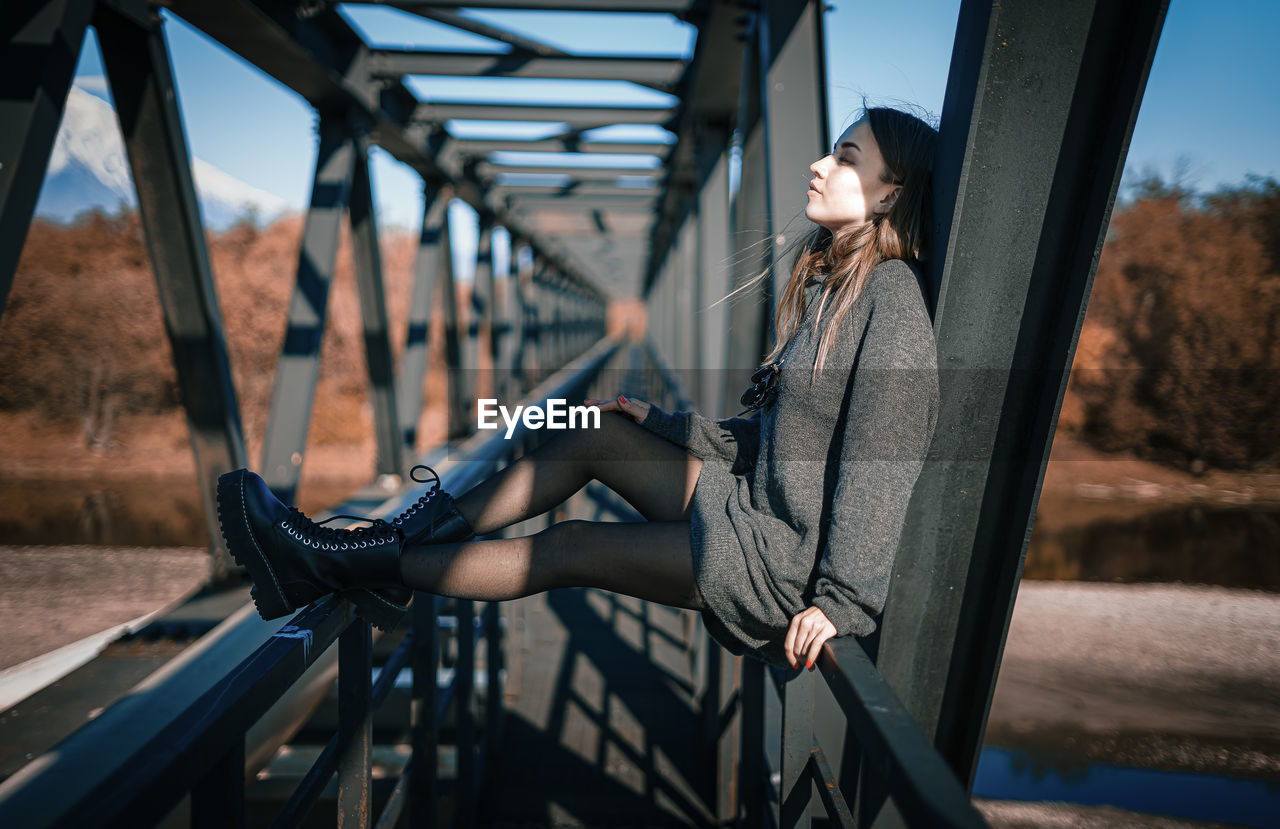 Woman on railing against bridge