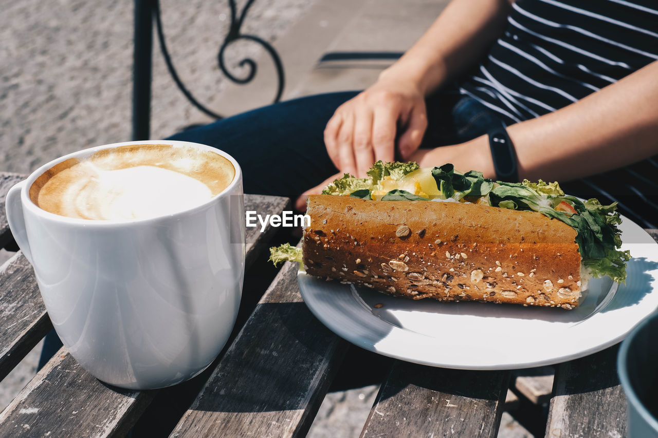 CROPPED IMAGE OF COFFEE CUP AND CAKE WITH CREAM