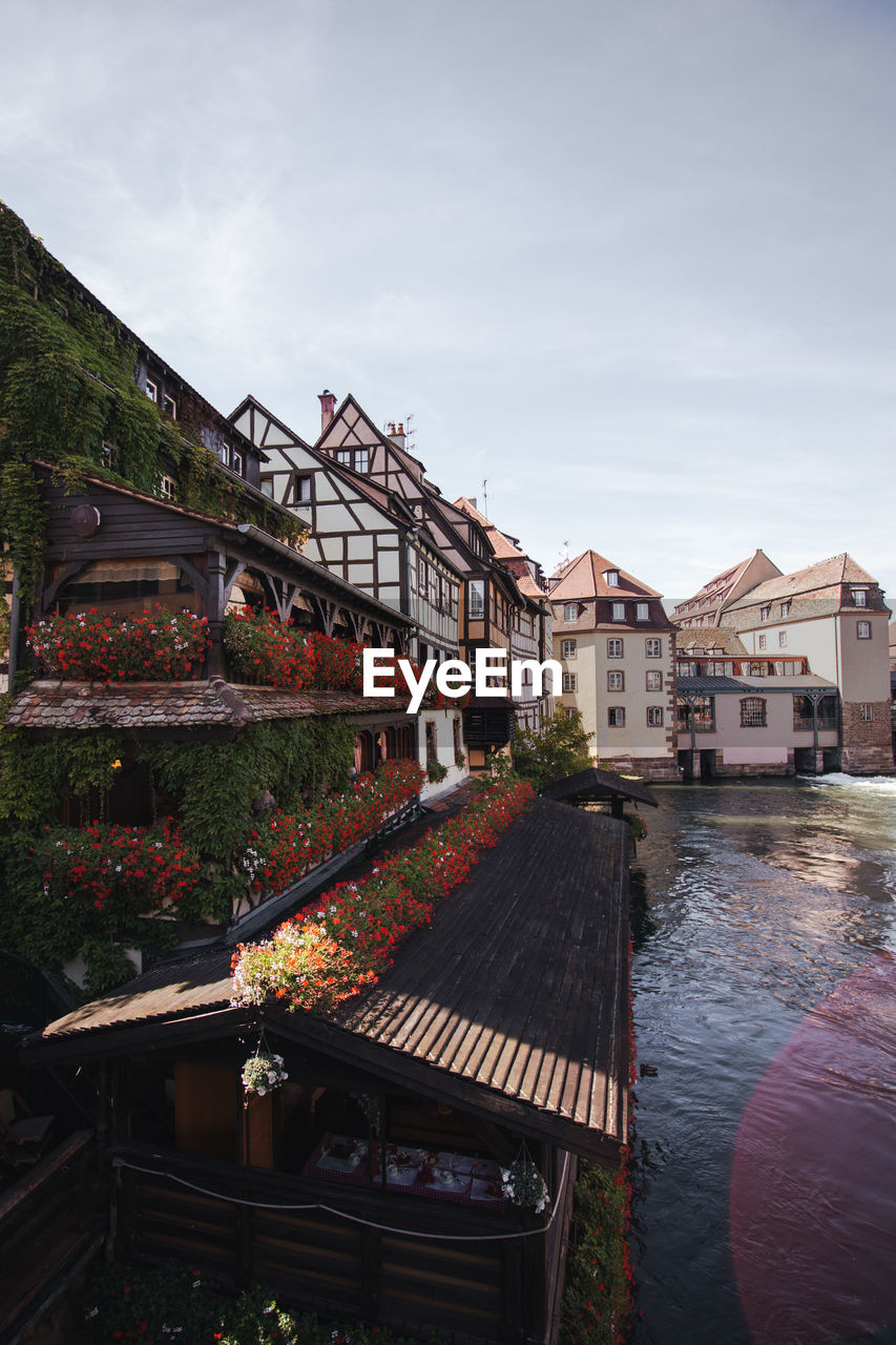 Houses by river and buildings against sky