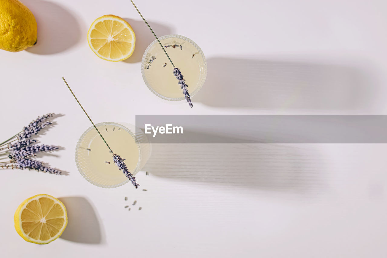 Still life with lavender infused lemonade and lemons on the white table with long shadows, top view