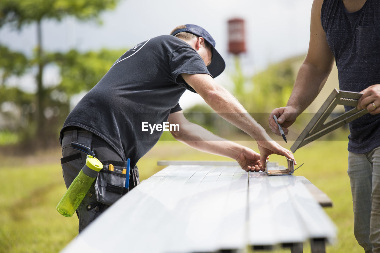 Two men marking measurements on steel excursion for solar panels.