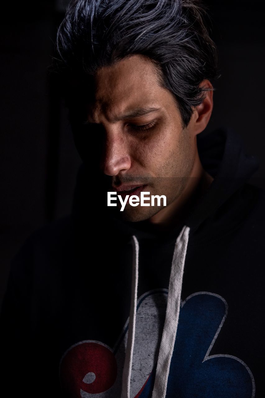 Close-up of thoughtful man against black background