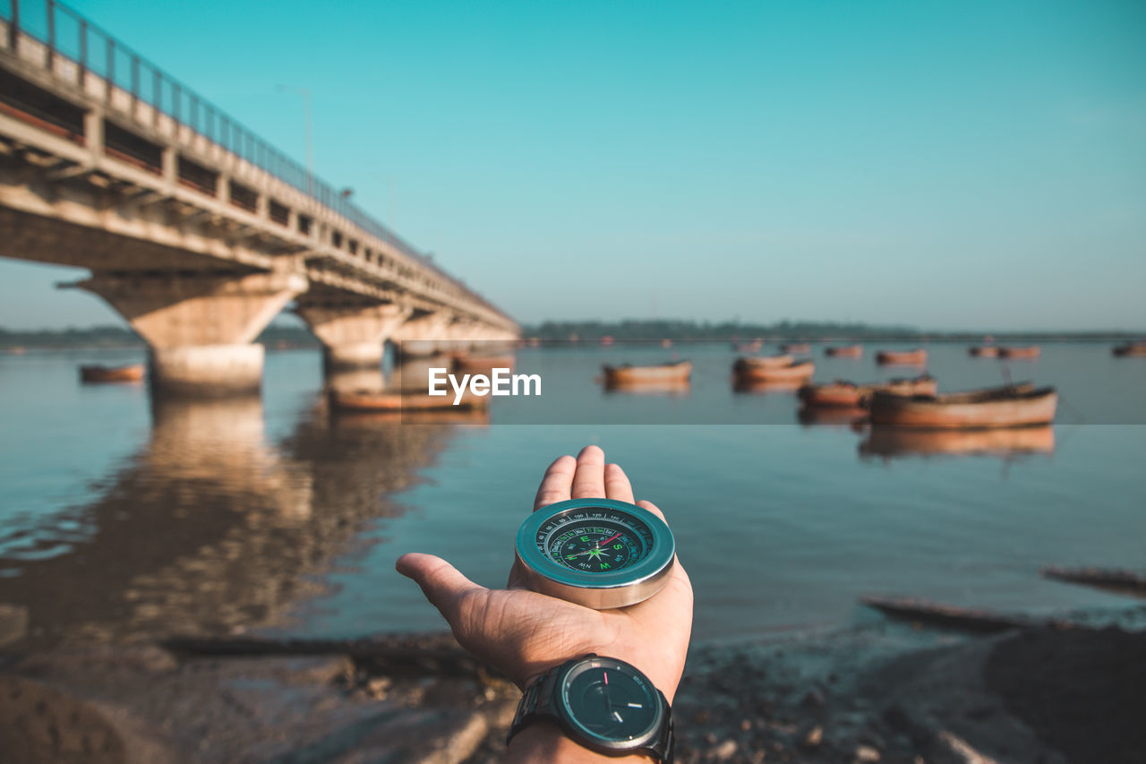 Man holding compass against river 