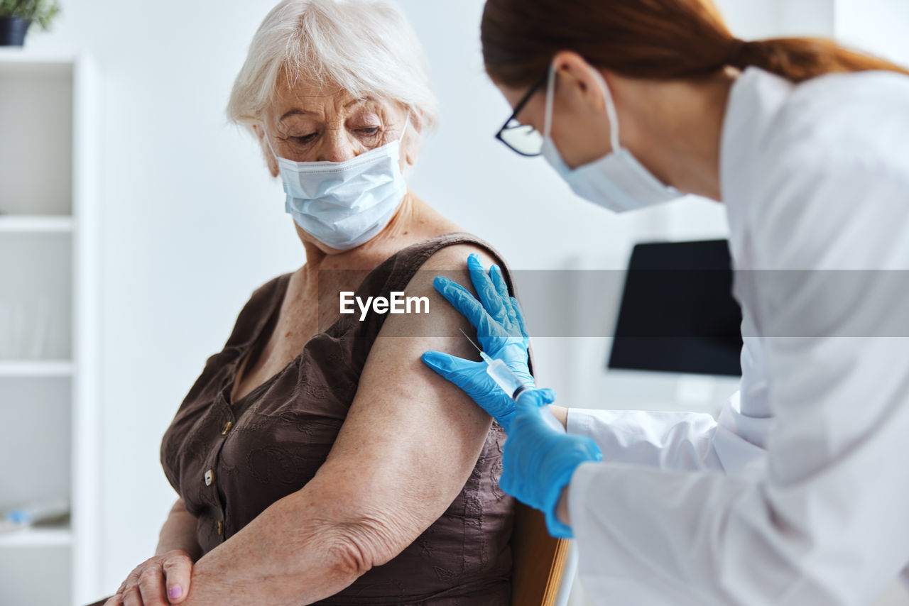 Doctor vaccinating senior patient at clinic