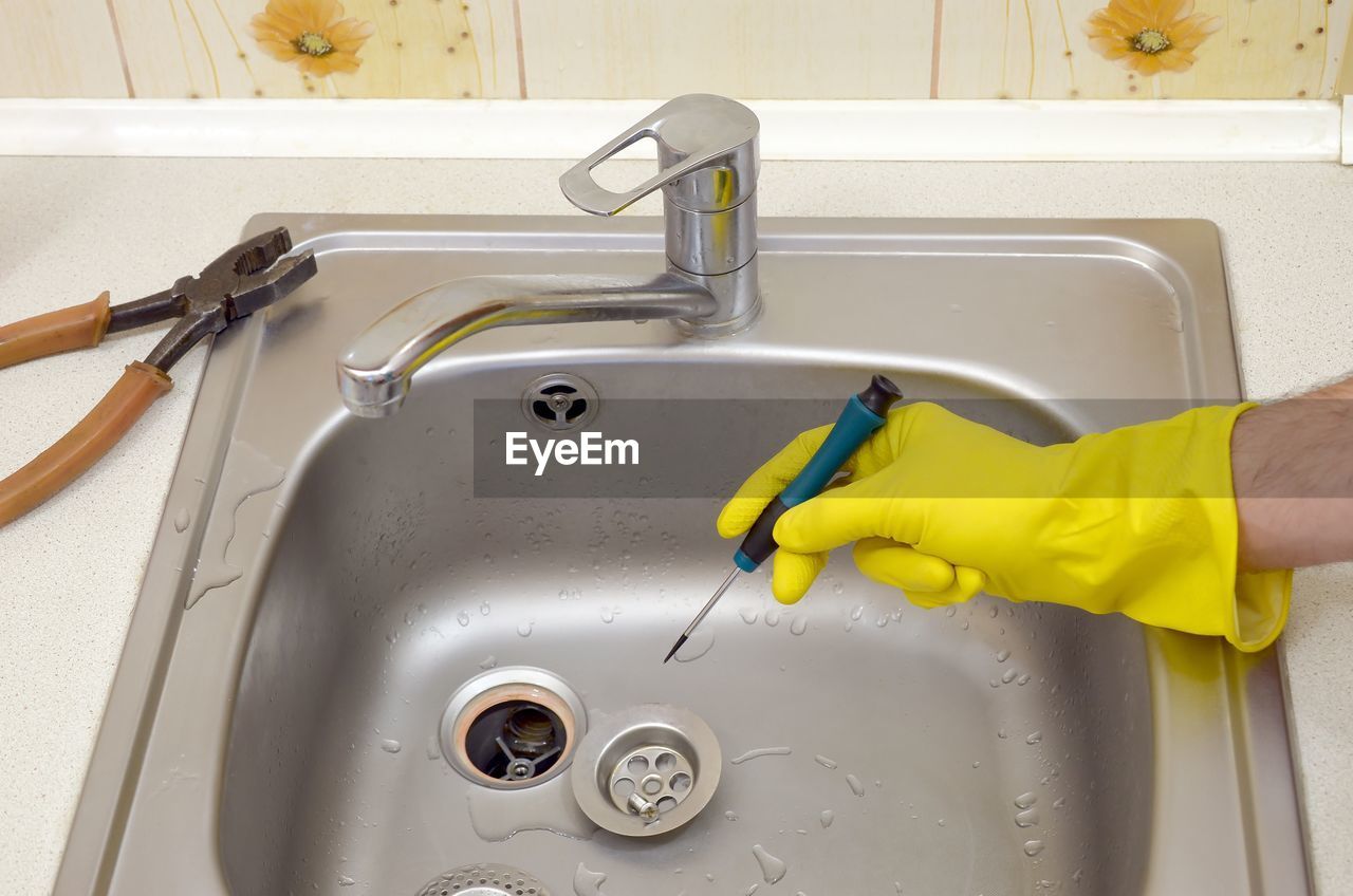 Cropped hand repairing sink