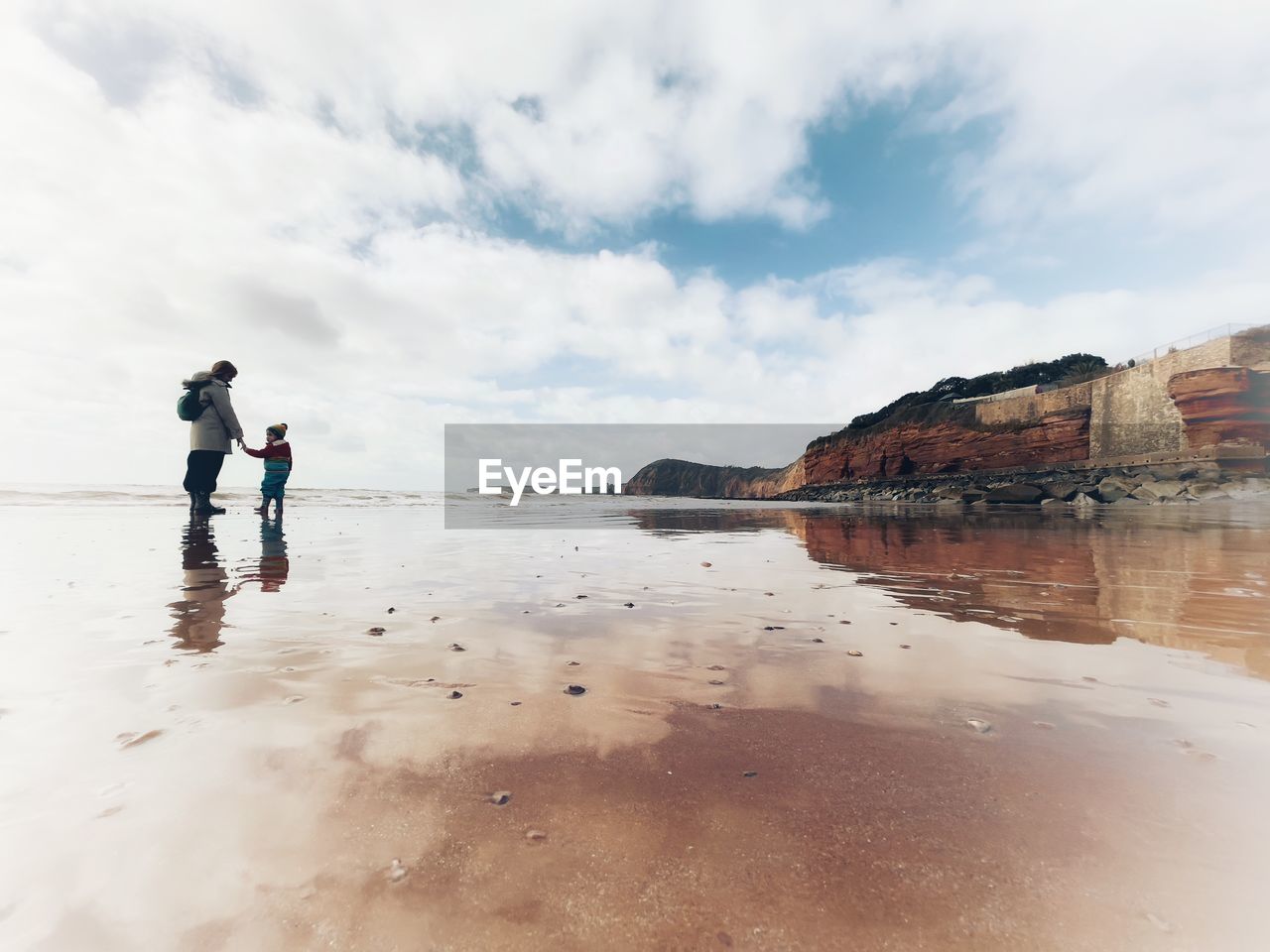 MAN STANDING ON BEACH AGAINST SKY