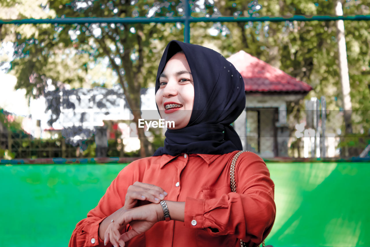 PORTRAIT OF SMILING YOUNG WOMAN