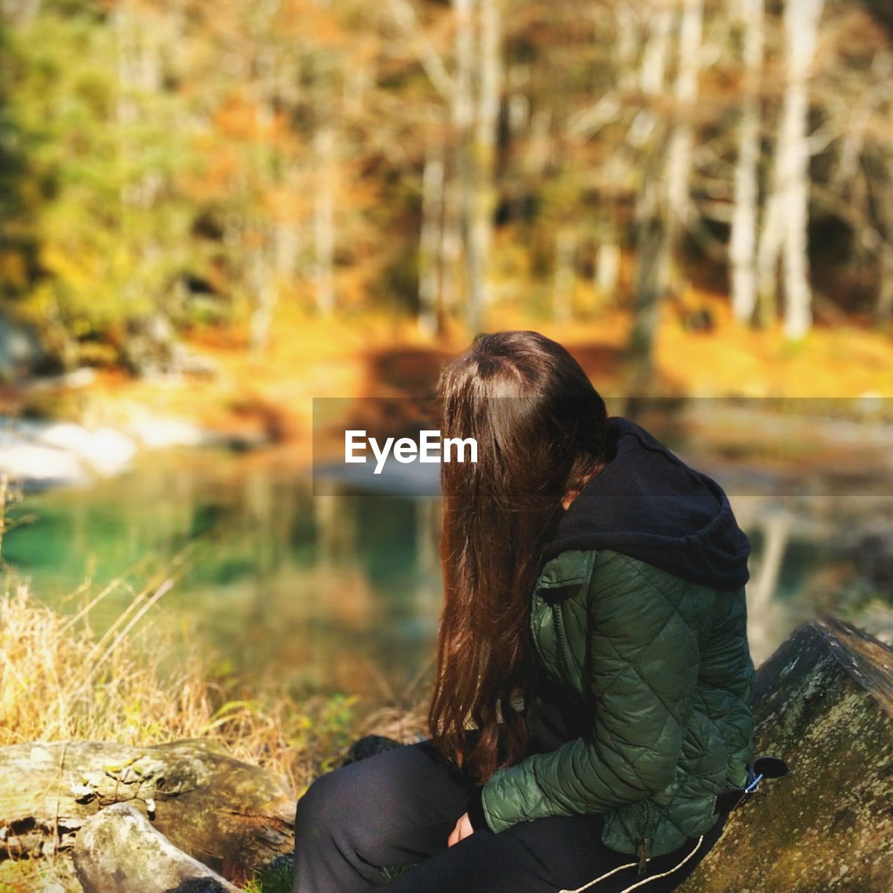 Side view of young woman sitting in forest