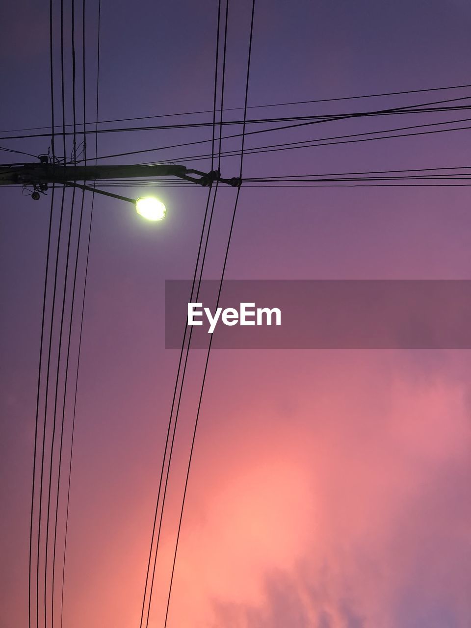 Low angle view of electricity pylon against sky during sunset