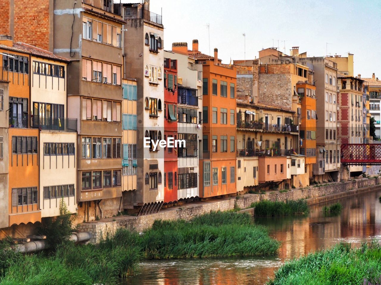 Residential buildings by river against sky