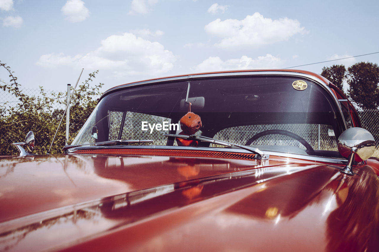 Close-up of red vintage car against sky