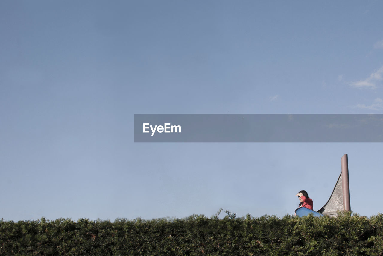 Side view of woman on landscape against blue sky