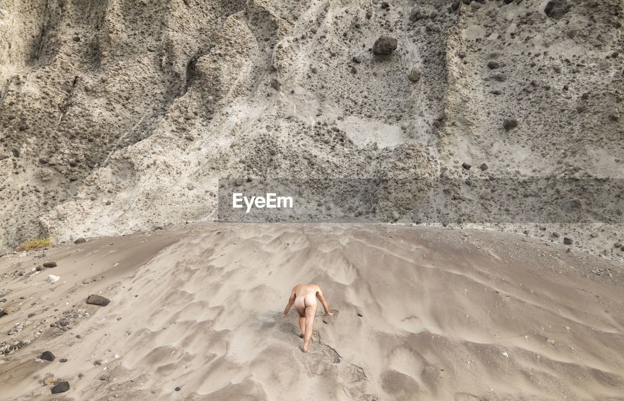 High angle view of shirtless adult man on beach against rock