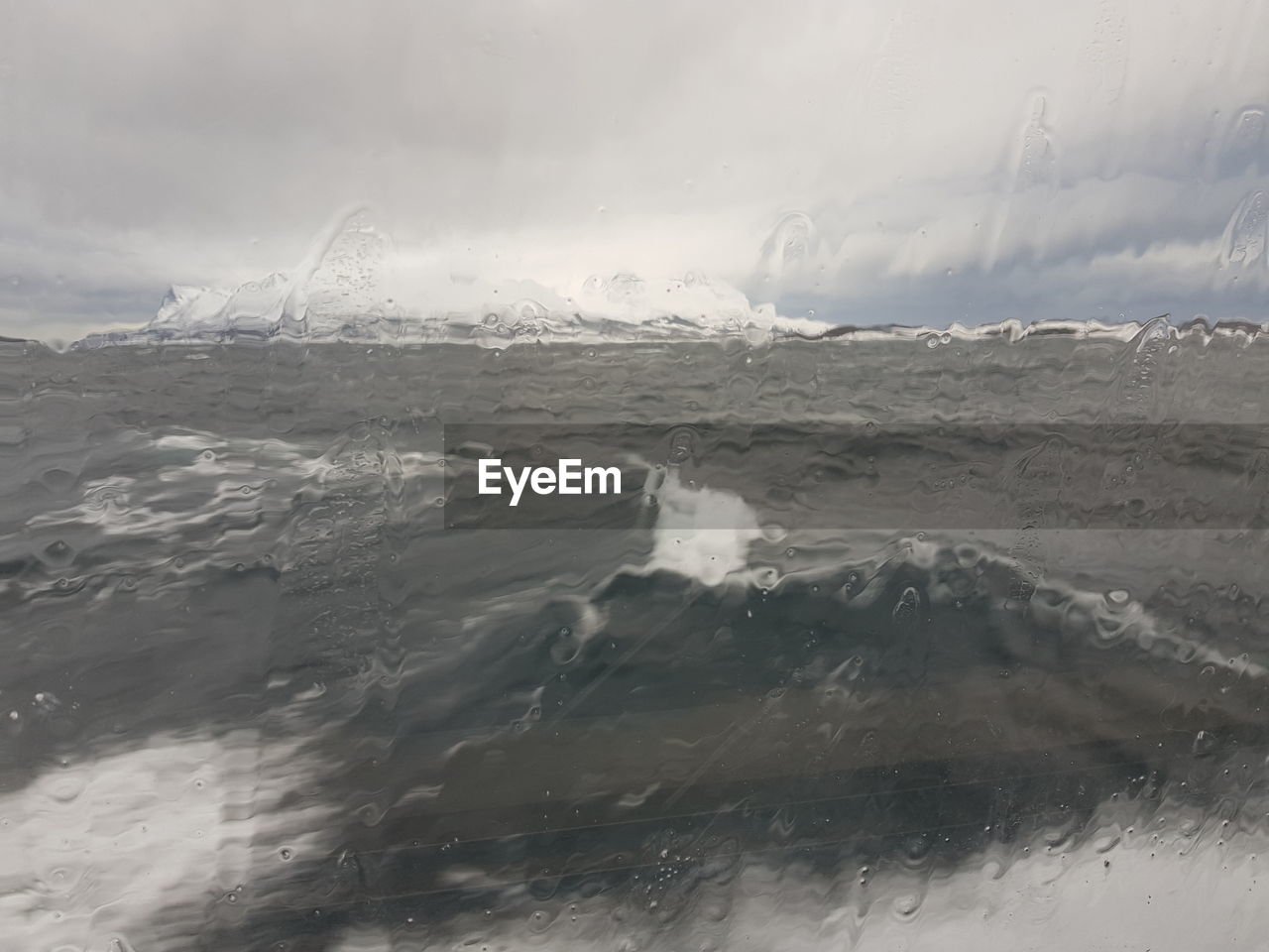 Scenic view of sea by snowcapped mountain against sky