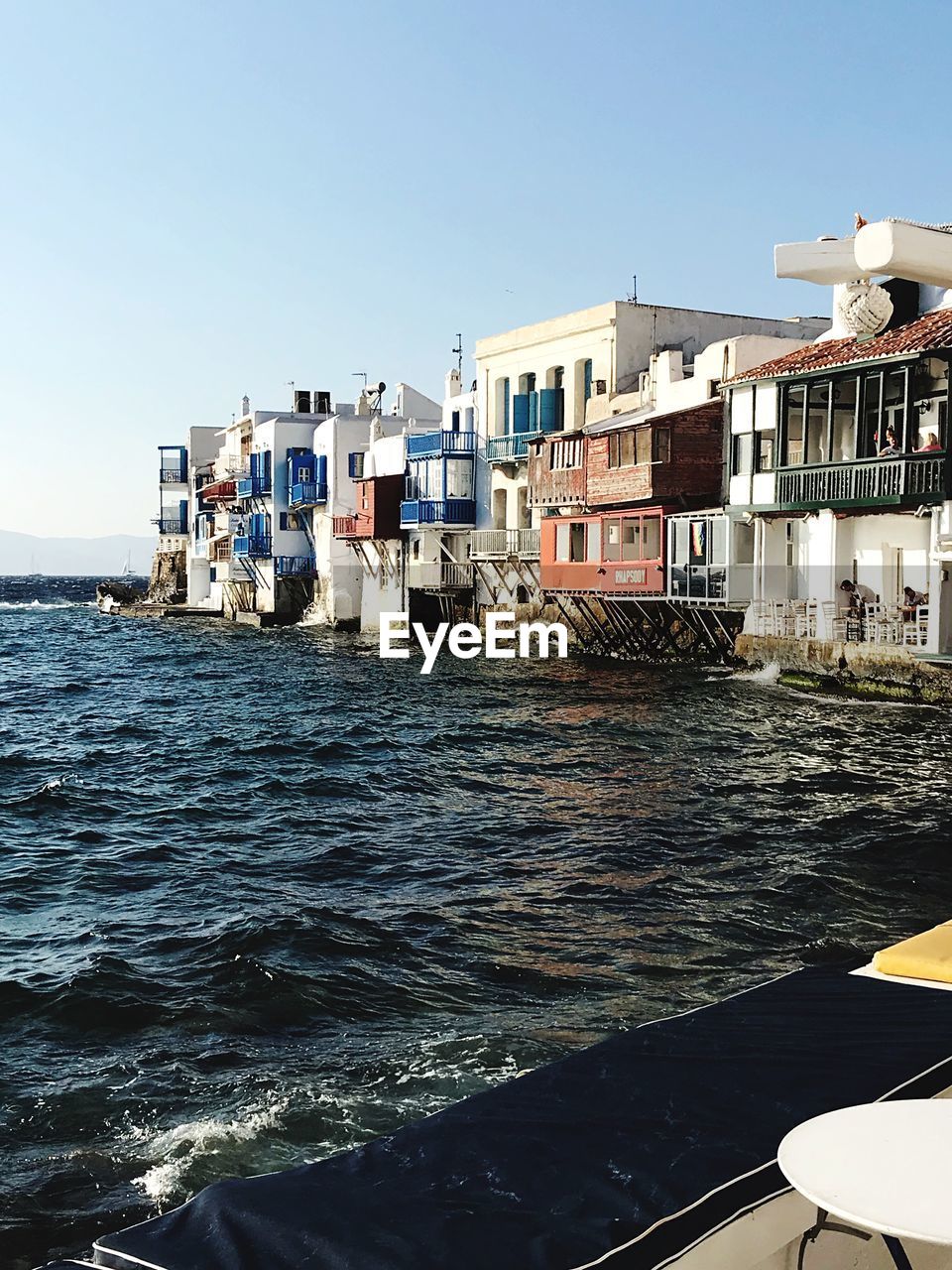 Buildings by sea against clear sky