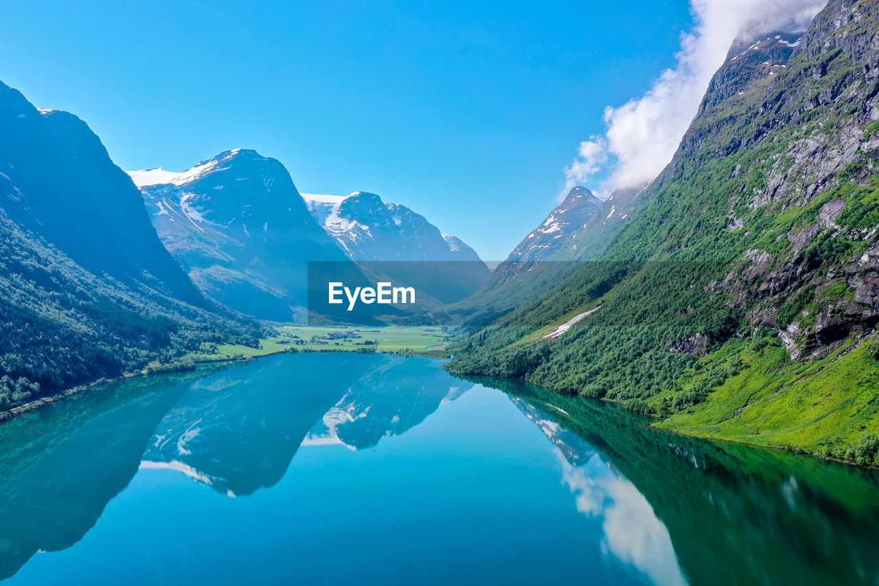 Scenic view of lake and mountains against blue sky