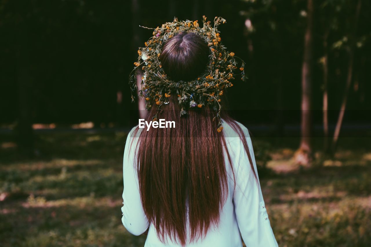 Rear view of woman wearing wreath in forest