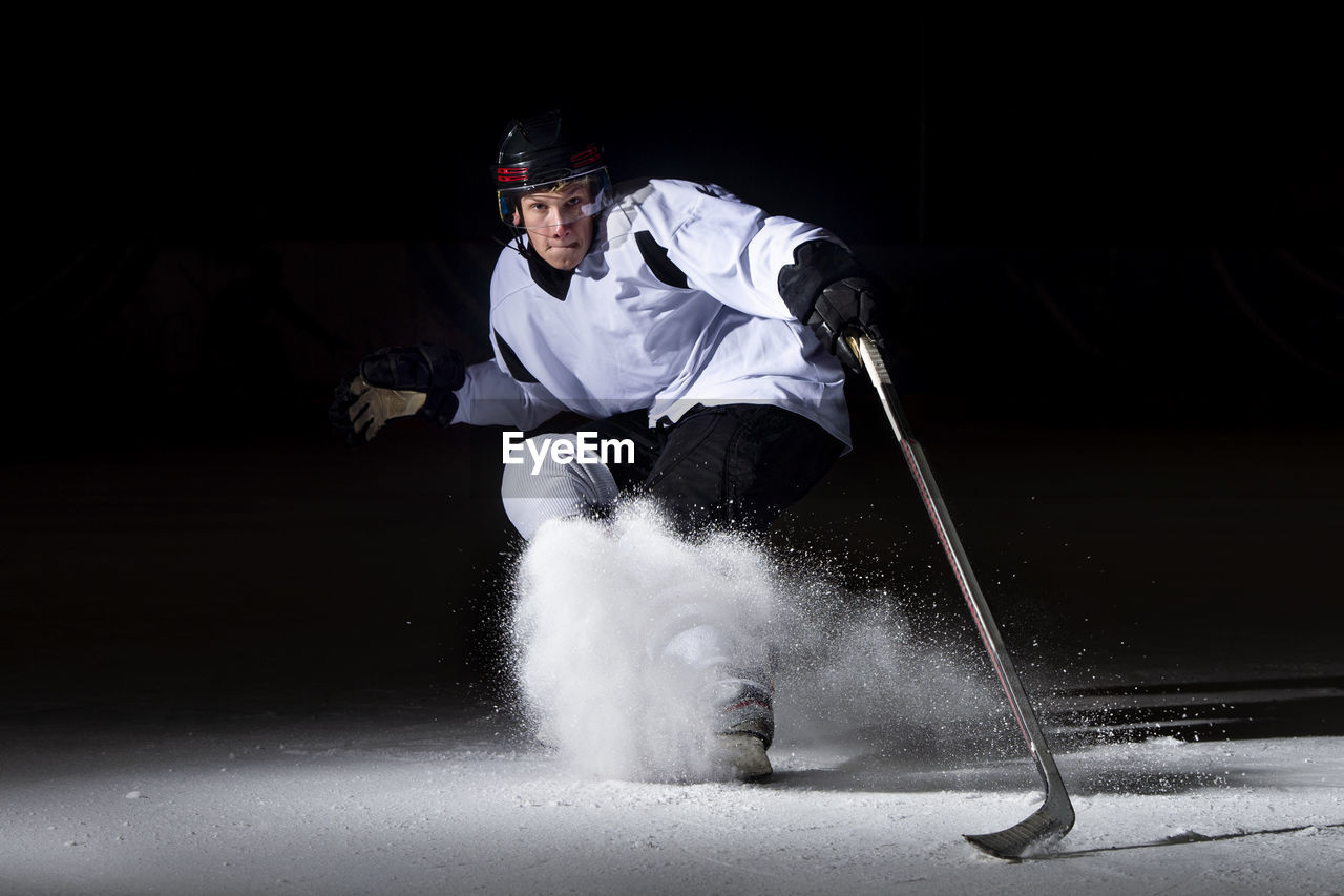 Portrait of man playing ice hokey at night