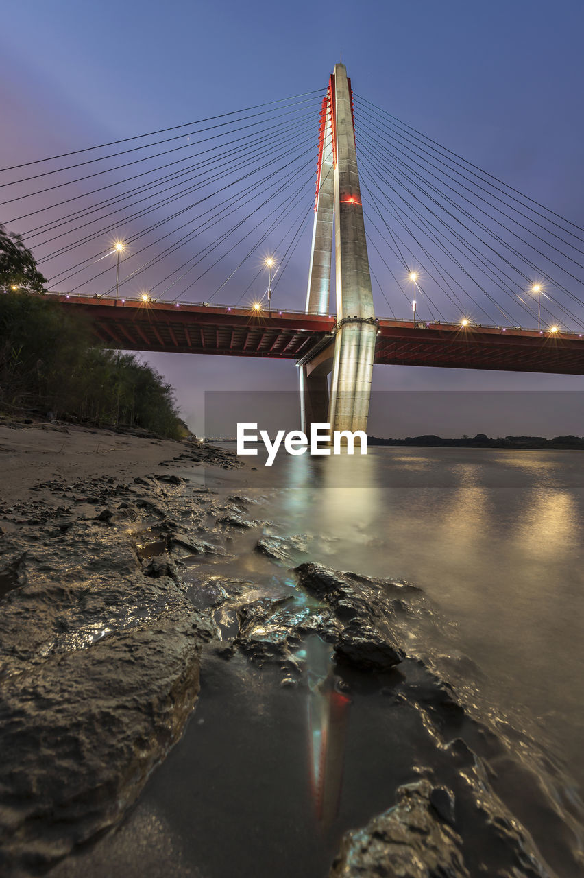 View of suspension bridge over river at night