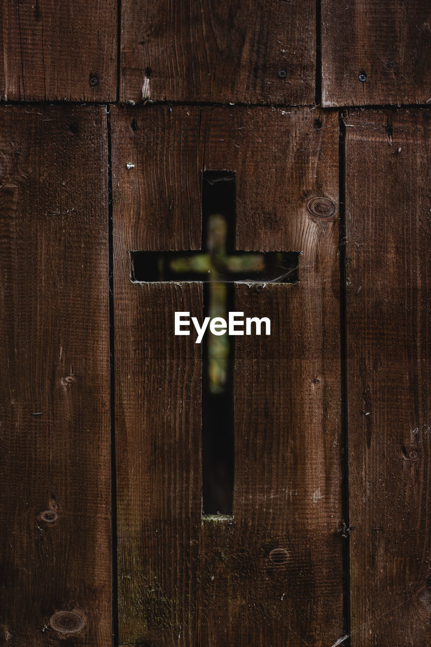 Close-up of a cross shape carved in wooden door